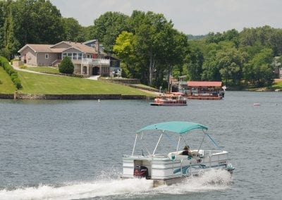 Boat Speeding Past on Lake with House in Distance